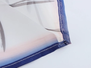 Dettaglio della trama in tessuto organza leggero con bordino blu e stampa di palme