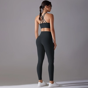 Detail of high-waist yoga pants and cross-strap sports bra in black performance fabric