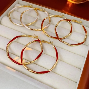 Macro detail of enamel drip gold metal hoop earrings in white, orange, and red colors