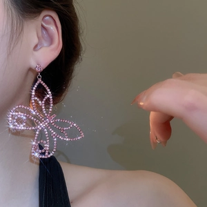 Macro shot of elegant long butterfly drop earrings featuring pavé pink rhinestones