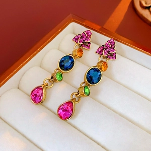 Detail of vintage French teardrop flower earrings with colorful gems on beige velvet