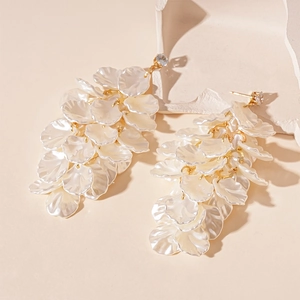Macro detail of elegant white acrylic flower petals and gold tassel drop earrings