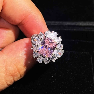 Macro view of flower-shaped ring with a pink emerald cut stone and diamond halo