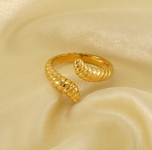 Macro detail of golden croissant ring with spiral texture on champagne silk background