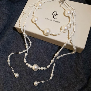 Macro detail of elegant layered pearl necklace with varying sizes on soft textile background