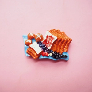Resin breakfast toast and bread fridge magnets set on a blue tray with pink background