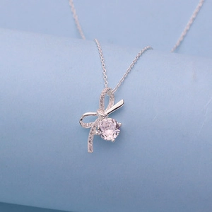 Macro detail of silver bow pendant with shimmering cubic zirconia stone inlay