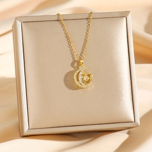 Golden heart and moon necklace with shimmering cubic zirconia on satin fabric