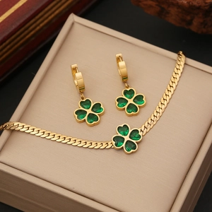 Detail of emerald green clover necklace and earrings set in gold Cuban link chain