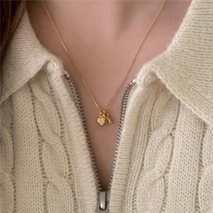 Close-up of gold 925 silver heart and key pendant necklaces on a knit sweater