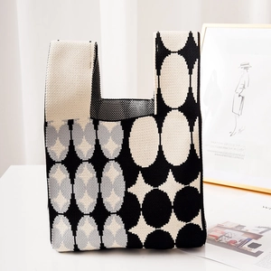 Minimalist knit handbag featuring black and white geometric patterns and top handle
