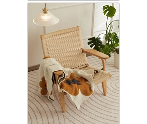 Detail of knitted sunflower throw blanket draped over a rustic wooden woven chair