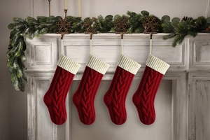 Close-up of four red cable-knit Christmas stockings hanging on a festive mantel