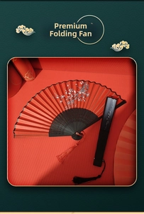 Detail of red folding fan with white plum blossom patterns and silk tassel