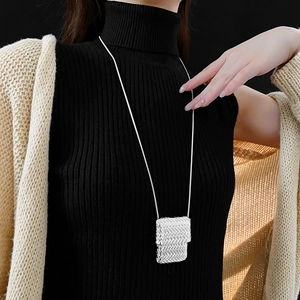 Detail view of square woven pendant necklace on snake chain over black sweater