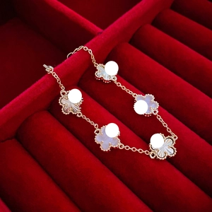Detail of five-clover gold-plated bracelet with milgrain edges on red velvet
