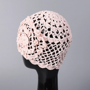 Détail d'un chapeau au crochet rose avec une fleur tricotée et perle blanche nacrée