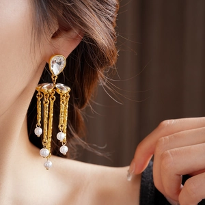 Detailed view of vintage gold earrings with crystal studs and pearl tassels on model