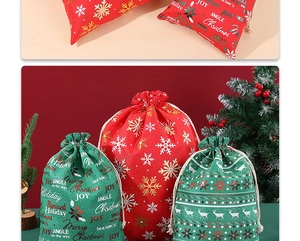 Close-up of red and green burlap Christmas gift bags with gold drawstring and reindeer prints