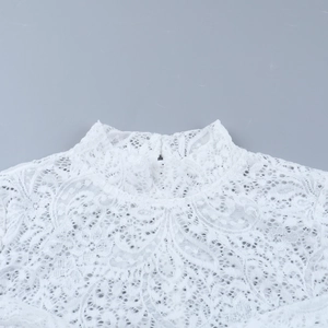 Primo piano dell'elegante scollatura in pizzo bianco con dettagli floreali traforati