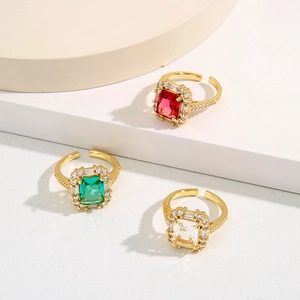 Détail de bagues en zircone rectangulaires rouge, vert et clair sur des supports blancs