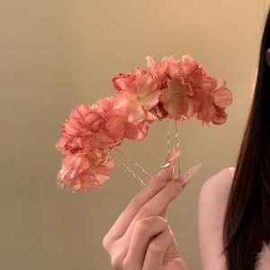 Detail of pink fabric flower hair pins with gold wavy metal sticks held by hand