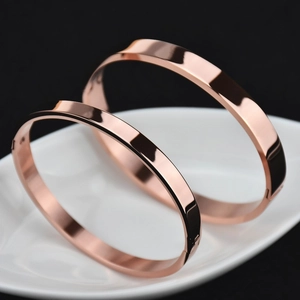 Set of two polished rose gold titanium steel bangles on a decorative tray