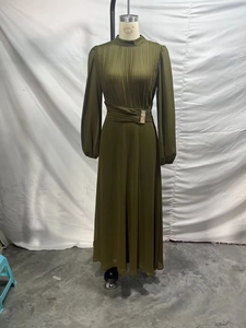 Detail of elegant dark green chiffon dress featuring a pleated bodice and gold buckle waist