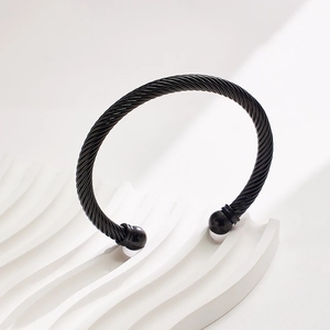 Detail of black twisted cable bangle with spherical ends on a white display stand