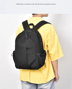 Back view of a black nylon backpack worn by a model against a white background