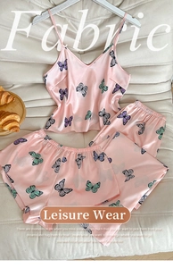 Detail of pink satin floral pajamas with butterfly print on textured sofa setting