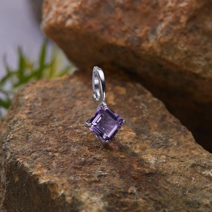 Macro shot of S925 silver pendant with square purple gemstone on a natural rock texture
