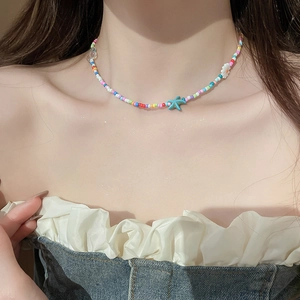 Detail of colorful beaded necklace featuring a teal starfish and white flower charm