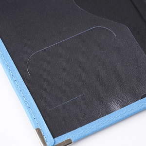 Detail of blue PU leather passport holder with black interior card slot and metal corner