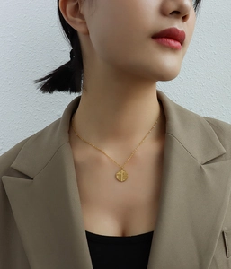 Model wearing a gold 18K titanium steel necklace with a round Fu character lucky pendant