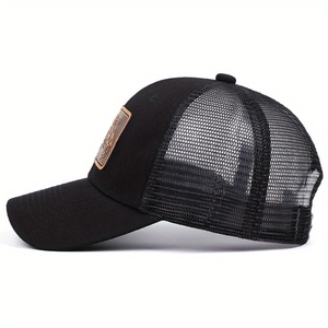 Detail of a black trucker hat featuring a leopard leather patch and breathable mesh back