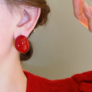 Close-up of elegant red oval stud earrings worn by a model for a stylish fashion look