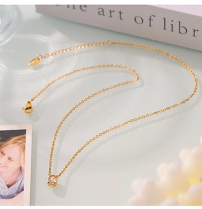 Detailed shot of a gold oval zircon pendant on a slim chain against a minimalist backdrop