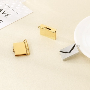 Macro shot of opening envelope and book pendants in gold and silver finish