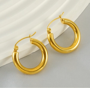 Close-up of polished 18K gold-plated stainless steel hoop earrings on textured stone