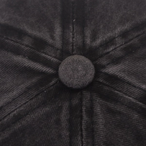 Macro shot of black winter beanie crown with reinforced stitching and fabric-covered button