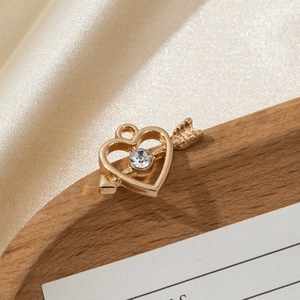 Detail of a golden heart arrow pendant with sparkling zircon on silk fabric
