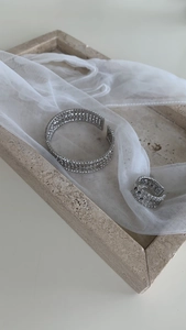 Detail of silver multi-layer zircon open cuff bracelet and matching ring on stone tray