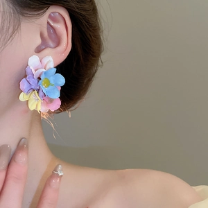 Detailed close-up of a model wearing a sweet colorful fabric flower stud earring