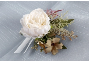 Detail of elegant white faux peony boutonniere with green leaves and white ribbon