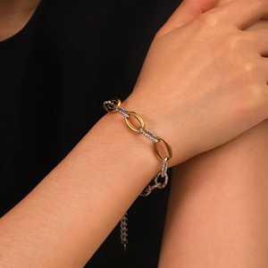 Close-up of mixed gold and silver link bracelet showing dual-tone texture on a wrist