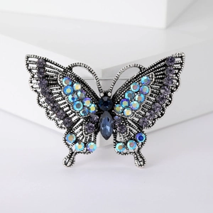 Detailed close-up of retro silver butterfly brooch with colorful rhinestones and hollow wings