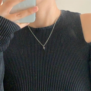 Detail of minimalist S925 silver star pendant necklace on a textured charcoal top