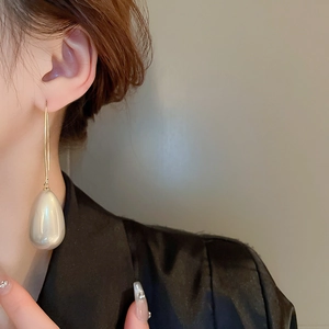 Gros plan d'une élégante boucle d'oreille en or avec une perle goutte blanche sur un modèle