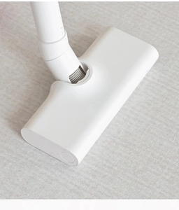 Close-up of a white vacuum brush attachment cleaning a cream-colored minimalist rug
